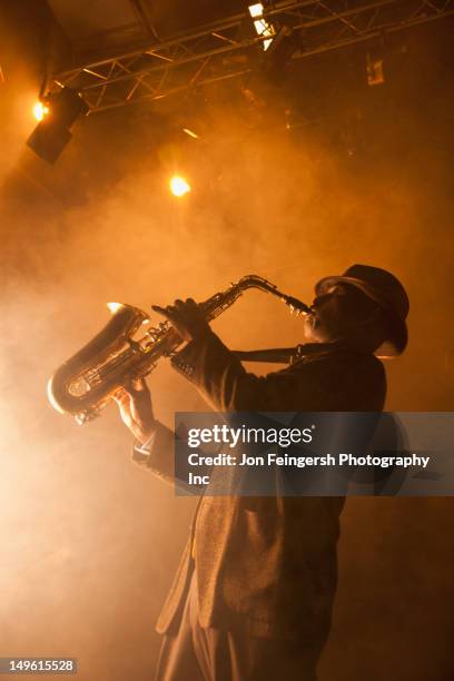 black musician playing saxophone on stage - sassofono foto e immagini stock