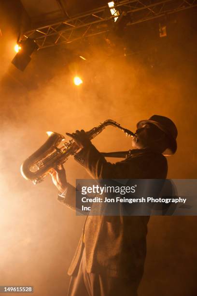 black musician playing saxophone on stage - saxophone stock pictures, royalty-free photos & images
