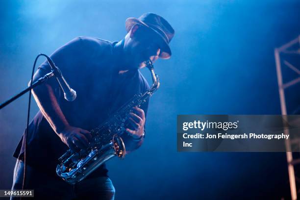 black musician playing saxophone on stage - saxofón fotografías e imágenes de stock