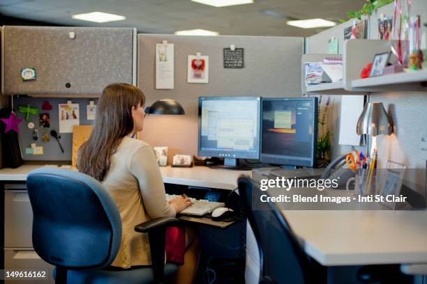 caucasian businesswoman working at desk in office - cubicle photos et images de collection