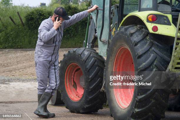 a farmer leans on his tractor and phone - michel field stockfoto's en -beelden