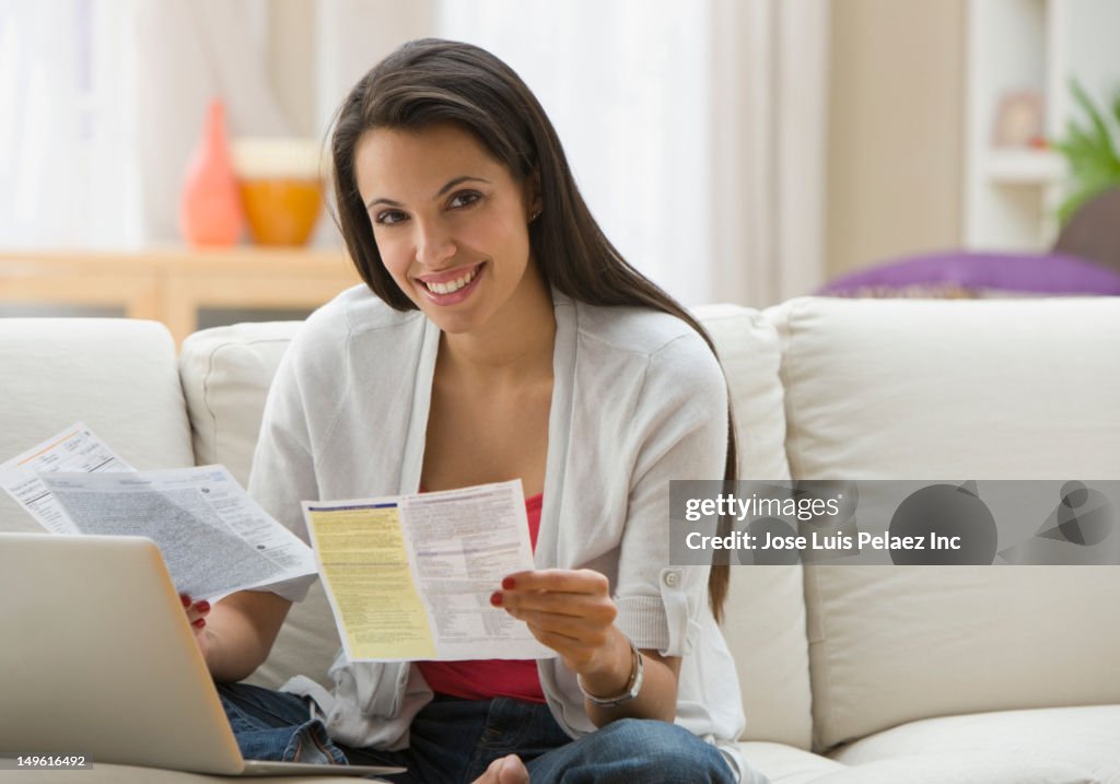 Hispanic woman paying bills online with laptop