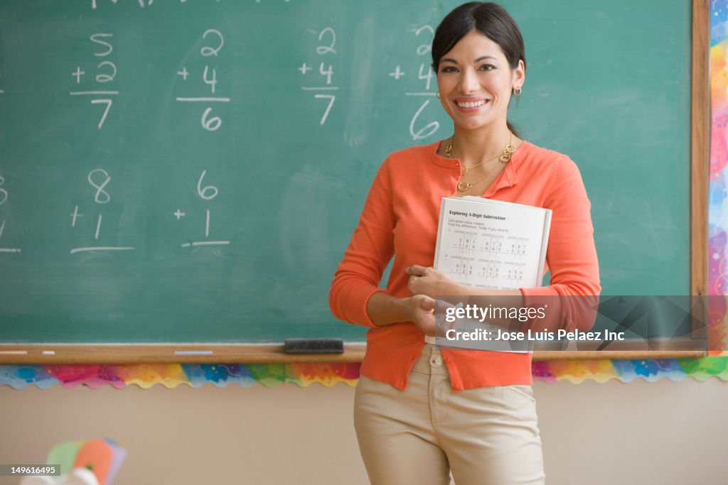 Mixed race teacher standing near blackboard