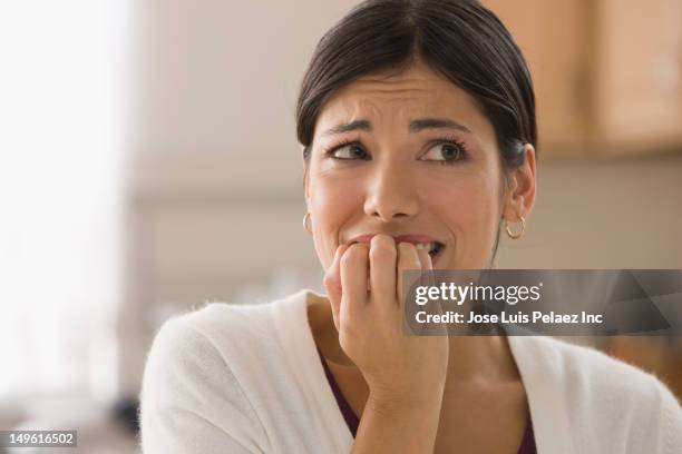 afraid mixed race woman biting fingers - anxiety foto e immagini stock