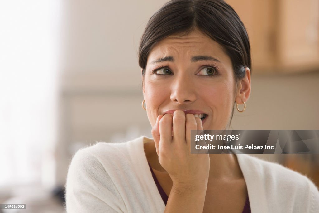 Afraid mixed race woman biting fingers