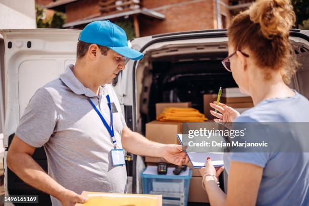 man working in delivery service asking for signature after delivery to customer - express delivery stock pictures, royalty-free photos & images