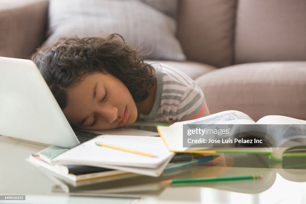 Tired Hispanic girl sleeping on laptop