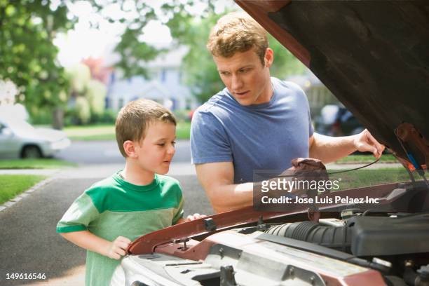 caucasian boy watching father work on car engine - oil change fotografías e imágenes de stock