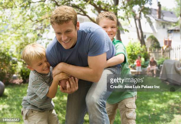 caucasian father and sons playing football - tackle american football player stockfoto's en -beelden