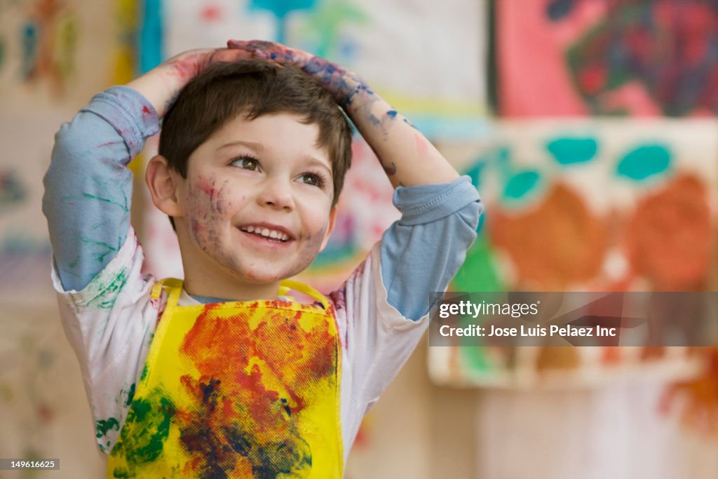 Messy Caucasian boy in art class