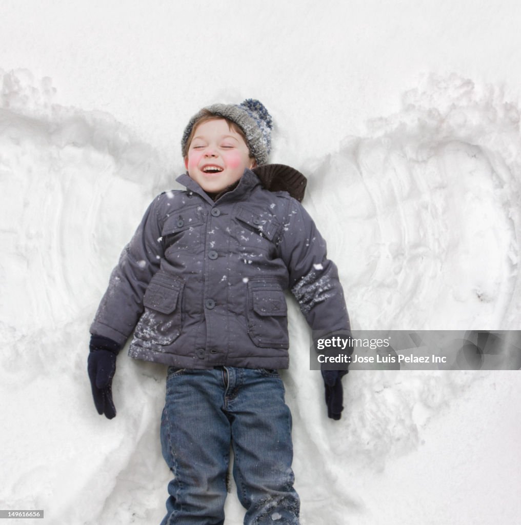 Caucasian boy making snow angel