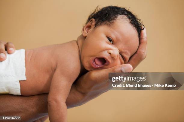 father cradling newborn baby in hand - cute black newborn babies stock-fotos und bilder