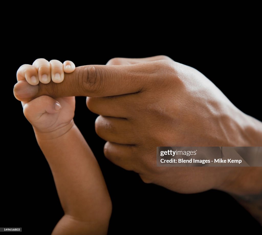 Father holding hands with newborn baby