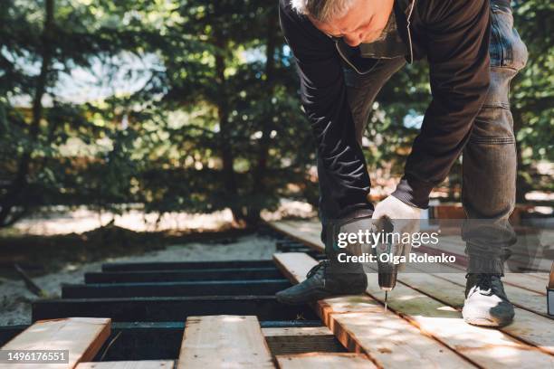 wooden board drill and construction: construction worker use drill to build a house outdoors during carpentry work - broca imagens e fotografias de stock