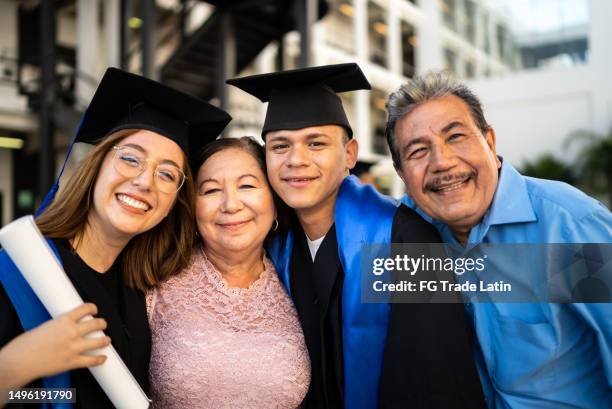 porträt junger hochschulabsolventen, die ihre eltern nach dem abschluss umarmen - abschlussfeier stock-fotos und bilder