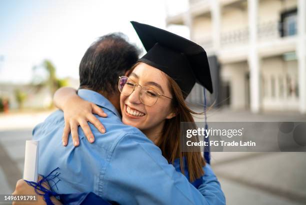 young graduate woman embracing father on her graduation - akademisk examen bildbanksfoton och bilder
