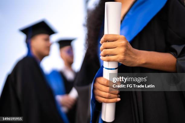 close-up of a young woman holding a diploma on graduation - scholarship award stock pictures, royalty-free photos & images