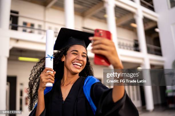 giovane donna che fa un selfie con il suo diploma sulla laurea - laurea foto e immagini stock