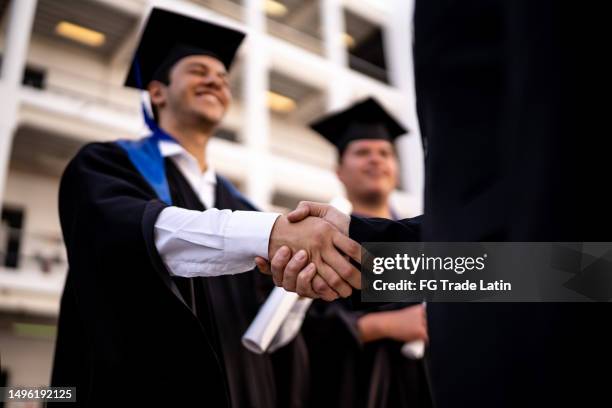 primer plano de un director felicitando y entregando el diploma a un joven estudiante por la graduación - túnica fotografías e imágenes de stock