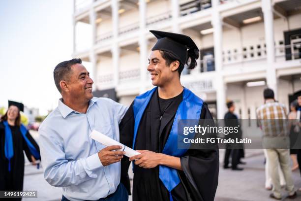 giovane laureato che parla con suo padre alla laurea - celebrazione della laurea foto e immagini stock