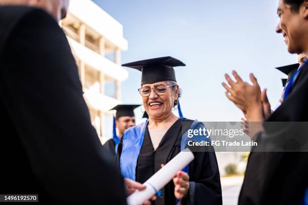 senior graduate woman receiving her diploma on graduation - graduation group stock pictures, royalty-free photos & images