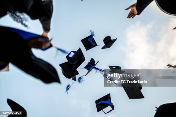 graduates throwing graduation cap in the air - throwing stock pictures, royalty-free photos & images
