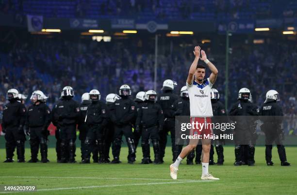 Francisco Montero of Hamburger SV applauds the fans as police are seen on the pitch after the team's defeat in the Bundesliga playoffs second leg...