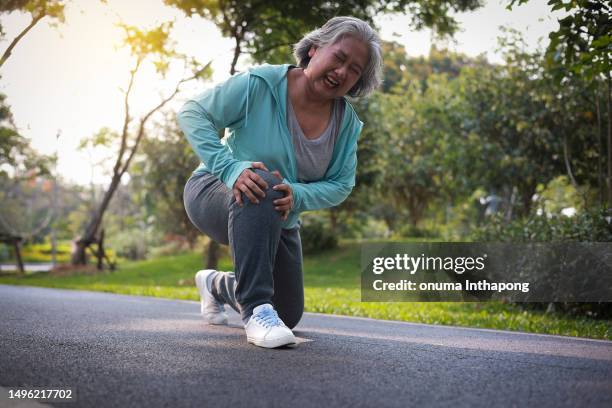 female elder having accident during jogging at park, exercise injury pain ache leg knee . - sprain stock pictures, royalty-free photos & images