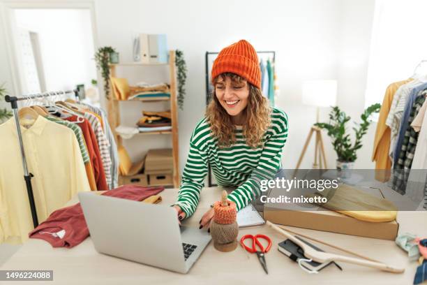 young beautiful woman using laptop at her home based clothing store - marktkoopman stockfoto's en -beelden