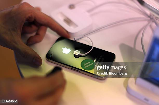 An employee handles an Apple Inc. IPhone 4S on display inside a re:Store, a premium Apple product reseller, in Moscow, Russia, on Wednesday, Aug. 1,...