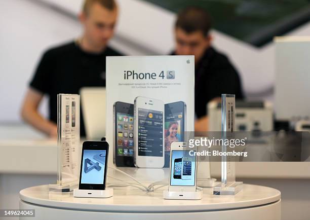 Employees stand near a display of Apple Inc. IPhone 4S mobile handsets at a re:Store, a premium Apple product reseller, in Moscow, Russia, on...