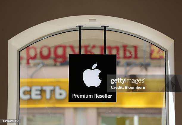 An Apple Inc. Logo hangs in the window of a re:Store, a premium Apple product reseller, in Moscow, Russia, on Wednesday, Aug. 1, 2012. OAO Mobile...