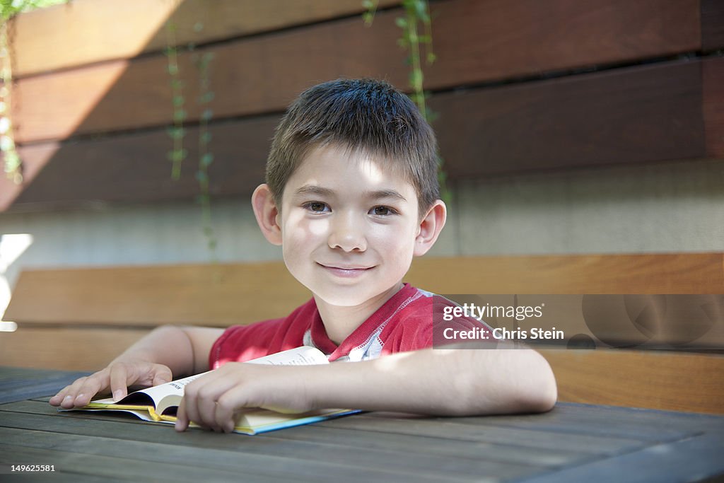 Young boy reading a book on a roof deck