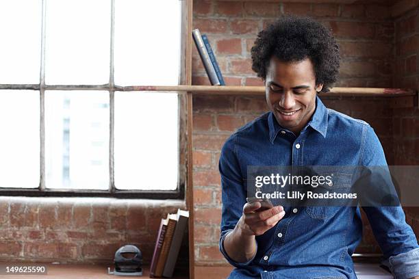 young guy sitting on desk using smartphone - business man looking at smart phone stock-fotos und bilder