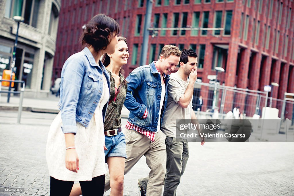 Four young adults crossing city street