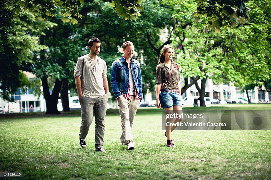 Three young adults walking in park
