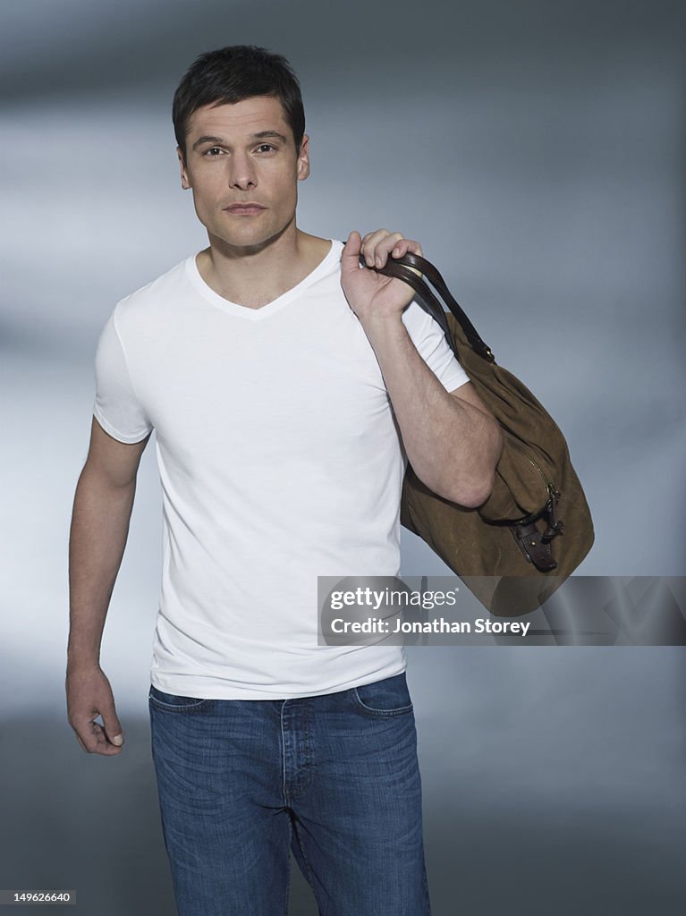 Man walking towards camera, bag over his shoulder