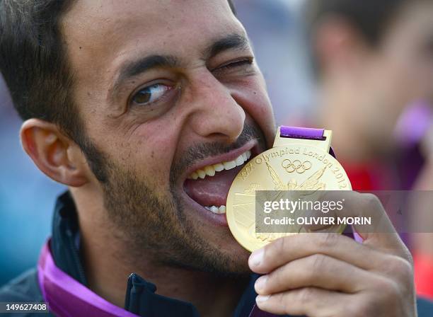 Gold medalist Italy's Daniele Molmenti bites his medal as he celebrates on the podium after winning the Kayak Single Men final at the " Lee Valley...