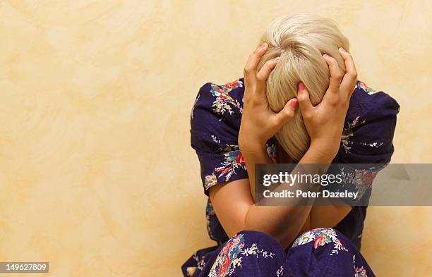 woman clutching her head in mental anguish - preoccupato foto e immagini stock