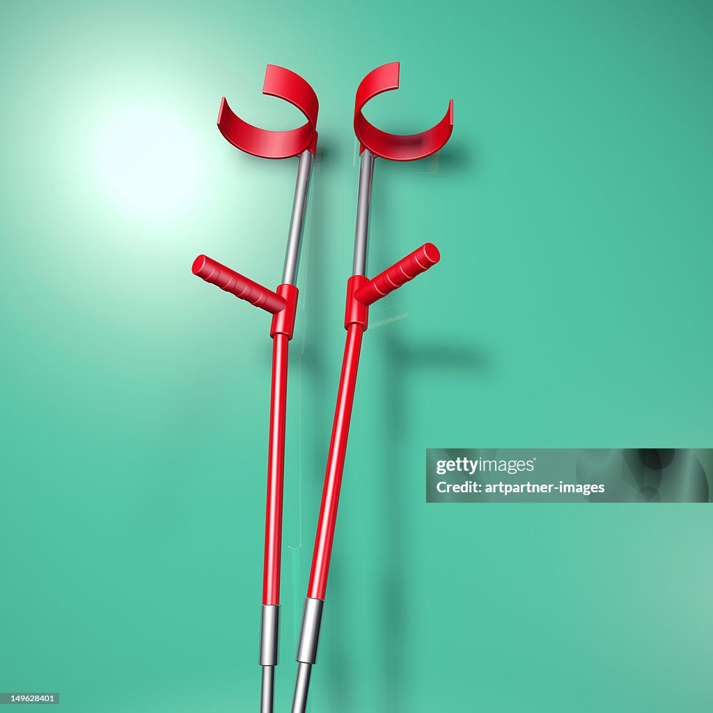 Red Crutches resting on a plain green background