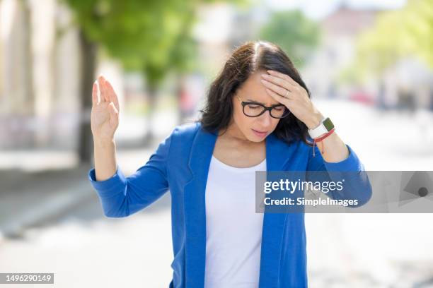 the young business woman suddenly feels dizzy and struggles to keep her balance. disoriented woman suffering from vertigo. - vertigine foto e immagini stock