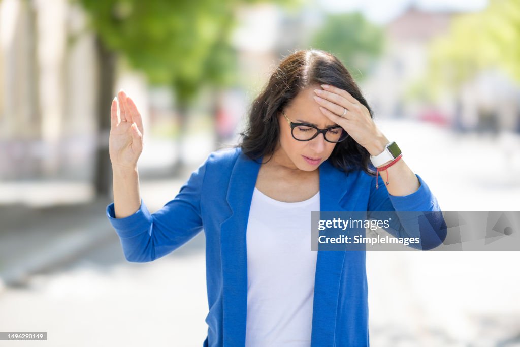 The young business woman suddenly feels dizzy and struggles to keep her balance. Disoriented woman suffering from vertigo.