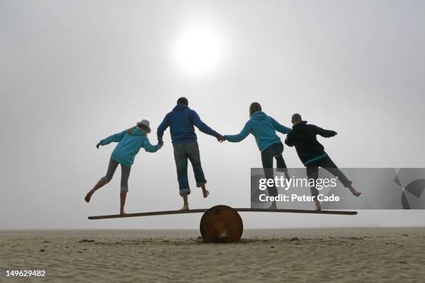 family balancing on beach - estabilidad fotografías e imágenes de stock