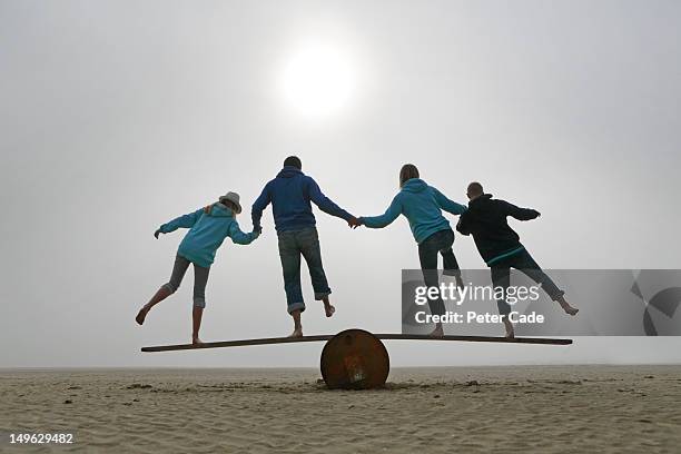 family balancing on beach - seesaw - fotografias e filmes do acervo