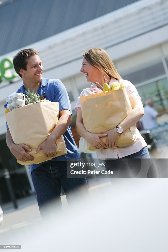 Couple walking away from supermarket with shopping