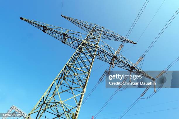 electricity pylon and cooling toweron a clear blue sky. - production d'énergie stock-fotos und bilder