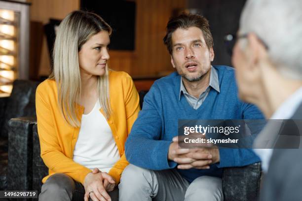 pareja de adultos medianos hablando con su agente en un vestíbulo. - terapia de pareja fotografías e imágenes de stock