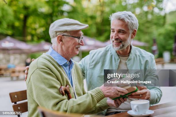 handsome man giving birthday gift to senior man. - generation x stock pictures, royalty-free photos & images