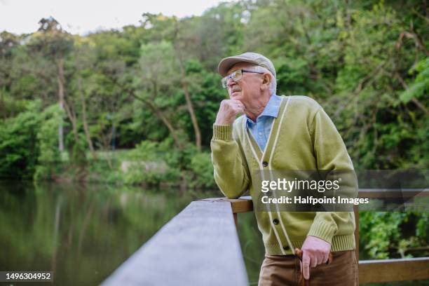 portriat of pensive senior man looking on lake. - viudo fotografías e imágenes de stock