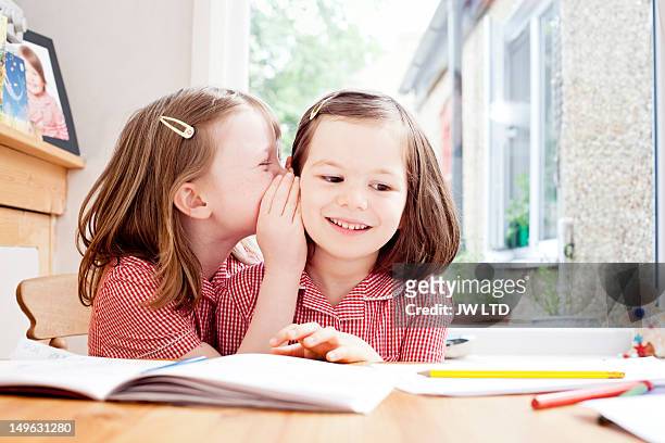 school girl whispering in girl's ear - confidential palabra en inglés fotografías e imágenes de stock